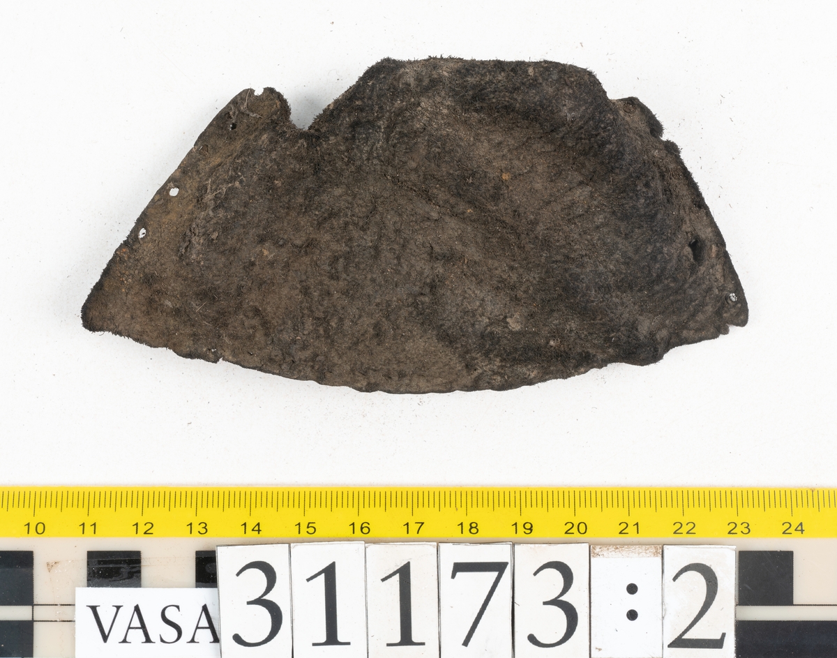 Dokumentation 1998:
Fem delar av överdelen till en slejfsko.
Ett ovanläder med bred och kantigt skuren plös, fyndnummer 31173. Längs med ovanlädrets ena sida och tvärs över tåpartiet löper stygnshål. Längs med ytterkanterna löper hål efter träpligg och stygn. Ovanlädrets främre parti och plös är något fragmentarsika. Lädret är kraftigt med fläckvisa, rostfärgade utfällningar.
En skuren läderremsa, fyndnummer 31173. Remsan har suttit fästad längs ovanlädrets ena sida. Längs med remsans ytterkanter löper hål efter stygn och träpligg.
Två stycken sidostycken med slejf. Sidostyckena har slutit om hälpartiet och fästats samman med en söm mitt bak på skon. Det vänsta sidostycket, fyndnummer 31173:1, är det bäst bevarade. I slejfänden finns ett urtag, troligtvis ett knapphål. Längs med ytterkanterna löper hål efter stygn. Längs den nedre kanten löper hål efter träpligg. Det högra sidostyckets nedre del samt slejfände är fragmentarisk. Lädret är kraftigt och relativt välbevarat.
En förstärkning, fyndnummer 31173:2. Troligtvis har lädret suttit fästat på ovanlädret och förstärkt tåpartiet. Lädret är kraftigt.

Dokumentation 2022:
Del av ovanläder. Framstycke till en sluten sko. Skapades på en rak läst och bars på vänster fot. Inga dekorationer. Fyndnummer 31173:1 är skons bakkappa och den har skador som liknar de från fyndnummer 09806. Fyndnummer 31173:3 är skons sidofoder. Ovanlädrets framstycke och bakkappan saknar vissa fragment och det finns tecken på förstärkningar. Ovanlädrets framstycke har haft förstärkningar på sidans insida och på tån, men de saknas idag. 
För mer information, se Länkade filer: Uppritning

Text in english:
These are a vamp and a quarter of a shoe, made of leather, made on a straight last and worn on the left foot, with no decorative features. 31173:1 represents the quarter and has suffered damage similar to 09805, 31173:3 represents the side lining. There are missing fragments from the vamp and the quarter and there are signs of reinforcements. The vamp had internal reinforcement (missing) only on its lateral side and at the toe.
For more information, go to Länkade filer: Uppritning