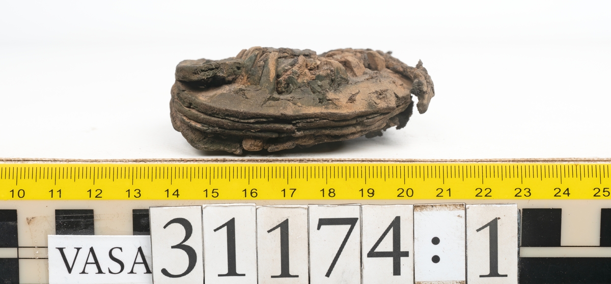 Delar av skobotten.
En sula med kvarsittande del av klacken. Sulan ligger vikt samt är delvis fragmentarisk. Längs med ytterkanterna löper hål efter stygn. Klacken består av fyra klacklappar. Två klacklappar är mycket fragmentariska. Klacken har kvarsittande tråd och träpligg.
En sula. Längs med ytterkanterna löper hål efter träpligg och stygn. Tåpartiet är något fragmentariskt. Lädret är mycket kraftigt.
En klacklapp. Klacklappen är något hästskoformad. På klacklappen syns stora hål efter träpligg.