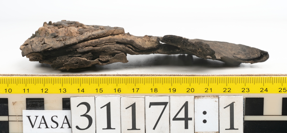 Delar av skobotten.
En sula med kvarsittande del av klacken. Sulan ligger vikt samt är delvis fragmentarisk. Längs med ytterkanterna löper hål efter stygn. Klacken består av fyra klacklappar. Två klacklappar är mycket fragmentariska. Klacken har kvarsittande tråd och träpligg.
En sula. Längs med ytterkanterna löper hål efter träpligg och stygn. Tåpartiet är något fragmentariskt. Lädret är mycket kraftigt.
En klacklapp. Klacklappen är något hästskoformad. På klacklappen syns stora hål efter träpligg.