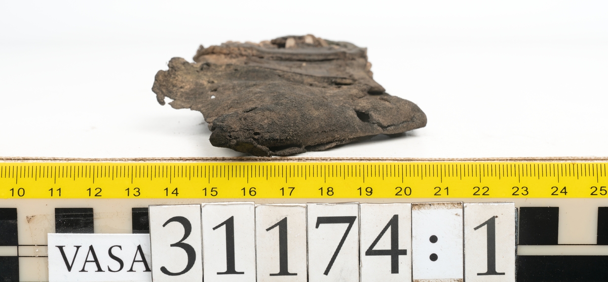 Delar av skobotten.
En sula med kvarsittande del av klacken. Sulan ligger vikt samt är delvis fragmentarisk. Längs med ytterkanterna löper hål efter stygn. Klacken består av fyra klacklappar. Två klacklappar är mycket fragmentariska. Klacken har kvarsittande tråd och träpligg.
En sula. Längs med ytterkanterna löper hål efter träpligg och stygn. Tåpartiet är något fragmentariskt. Lädret är mycket kraftigt.
En klacklapp. Klacklappen är något hästskoformad. På klacklappen syns stora hål efter träpligg.