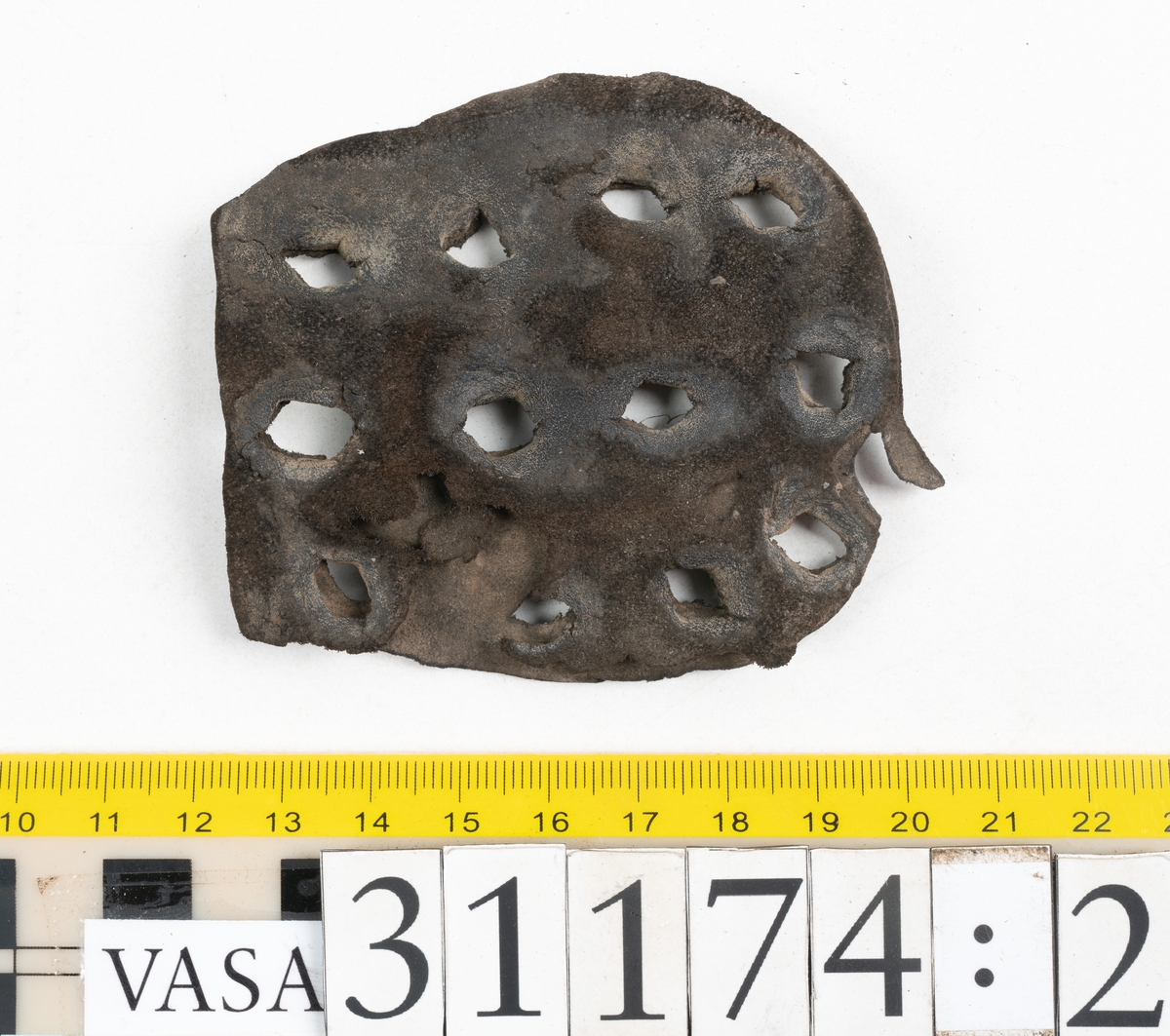 Delar av skobotten.
En sula med kvarsittande del av klacken. Sulan ligger vikt samt är delvis fragmentarisk. Längs med ytterkanterna löper hål efter stygn. Klacken består av fyra klacklappar. Två klacklappar är mycket fragmentariska. Klacken har kvarsittande tråd och träpligg.
En sula. Längs med ytterkanterna löper hål efter träpligg och stygn. Tåpartiet är något fragmentariskt. Lädret är mycket kraftigt.
En klacklapp. Klacklappen är något hästskoformad. På klacklappen syns stora hål efter träpligg.