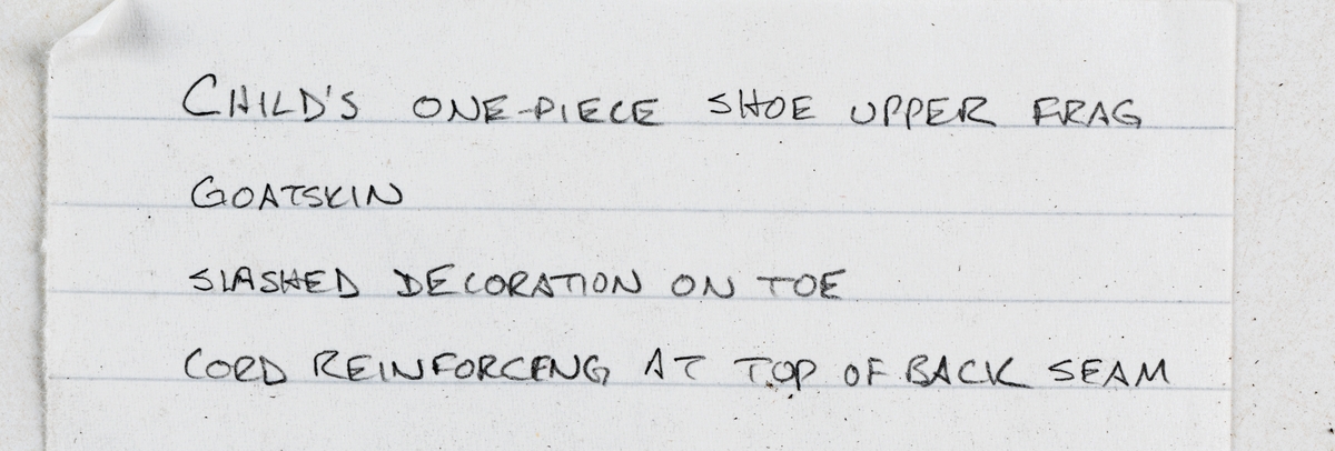 Dokumentation 1998:
Delar och fragment från sko.
En sula. Längs med sulans ytterkanter löper hål efter stygn med kvarsittande tråd. Vid hälpartiet samt samt längs ena sidan finns flera hål efter träpligg. Lädret är kraftigt och välbevarat.
Ett sidostycke med slejf. I änden på slejfen finns ett knapphål. Längs två av sidorna löper stygnshål. Lädret är spaltat och delvist fragmentariskt.
Ett ovanläder. Plösen är rakt skuren samt försedd med två snörhål. Längs med ytterkanterna löper stygnshål. Ovanlädrets ena sida är fragmentarisk och delar av sidan saknas. Lädret är spaltat.
Ett 150-tal delar och fragment av bl a holtrand, inlägg, sulor mm. På lädret syns hål efter stygn och träpligg Flertalet fragment är mycket små. Lädret är spaltat och mycket fragmentariskt.

Dokumentation 2022:
Ovanläder till en toffla. Tillverkad i getskinn med dekorativa hål på ovanlädrets framstycke. Har tillhört ett barn. Äldre än Vasa. Fragmenterad och förstärkt på insidan. 
För mer information, se Länkade filer: Uppritning

Text in english:
This is the upper of a slip-on shoe, made of goatskin leather, belonging to a child, decorative pinking across the vamp. The upper predates the Vasa, is fragmentary, and was reinforced on the inside.
For more information, go to Länkade filer: Uppritning