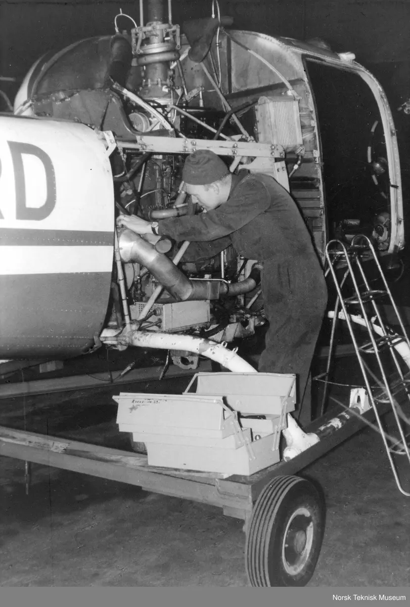 Tekniker Gulbrand Ruud under vedlikehold av Bell 47J helikopter fra Helikopter Service A/S på Fornebu ca. 1960