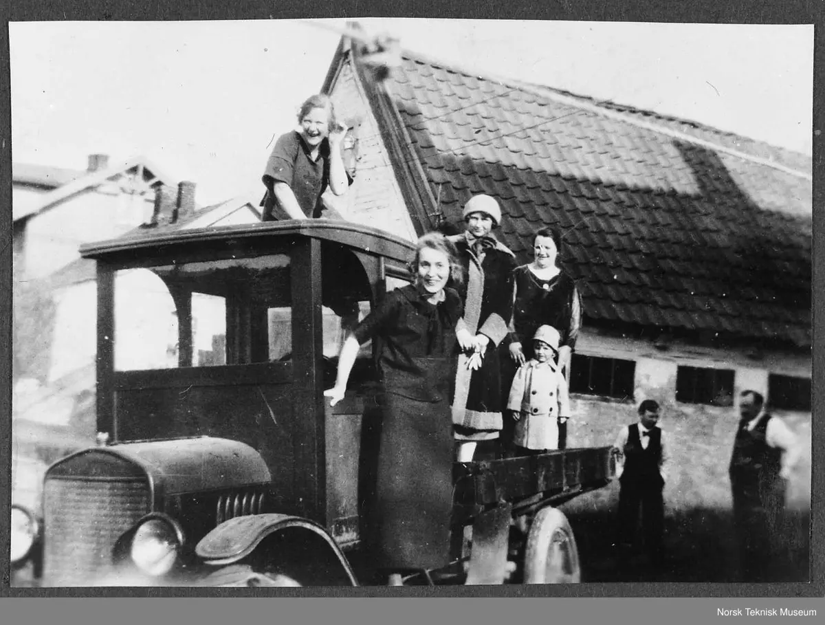 Søstrene Asbjørg og Aase Ramberg med svigerinnene Kirsten og Anna samt Annas lille sønn Kjell på lasteplanet til "1-ern", Ford TT 1923 : i bakgrunnen sønnen Hans og faren Axel Ramberg i gården i St. Halvardsgt. 52, Oslo