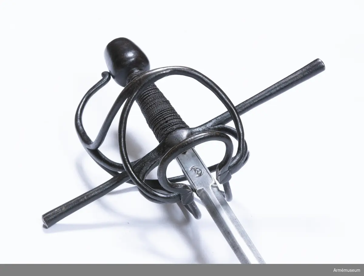 Den smala, tveeggade klingan har flata åsar. Längst upp har den en cirka 5 cm lång ansats, som har rektangulärt tvärsnitt. Ansatsen har på var sida längs långkanterna en ingraverad rand, och på var sida är en halvmåne inslagen. Stämpeln är en tysk efterbildning av Toledosmeden Juan de Lunas stämpel.

Fästet är av svärtat järn. Knappen har cirkelrunt tvärsnitt och  avsmalnar något uppåt. Översidan är svagt och undersidan är starkt avrundad. Nitknappen är närmast cylindrisk och skiljs nedtill genom en instrypning från den lilla avrundade foten. Halsen är kort, har cirkelrunt tvärsnitt och skiljs genom en instrypning från knappen. Träkaveln avsmalnar något uppåt. Dess eggsidor är flata, men flatsidorna är svagt kullriga. Upp- och nedtill finns en smal krans av snodd järntråd. Kavellindningen består av en ganska smal höger- och en liknande vänstersnodd järntråd, men ursprungligen har det tydligen funnits flera trådar.
Parerstången är rak och har cirkelrunt tvärsnitt. Den vidgas rätt mycket mot de svagt avrundade ändarna. Från korsets undersida går på var flatsida en kort trekantig flik nedåt. Från korset vid var och en av klingans eggsidor går en stor fingerhake nedåt. Fingerhakarnas nedre ändar förenas på yttersidan genom en horisontal "åsnehovsbygel" och från samma ändar utgår också en stor, snedställd parerbygel, vars översida står något över parerstången. Från mitten på sistnämda bygel går en spång till handbygeln, med vilka den förenas något nedanför bygelns mitt. På innersidan går en nedtill trekluven gaffelspång från fingerhakarnas nedre ändar till handbygeln, vilken den träffar något nedanför bygelns mitt. Alla byglar och spänger har cirkelrunt tvärsnitt.