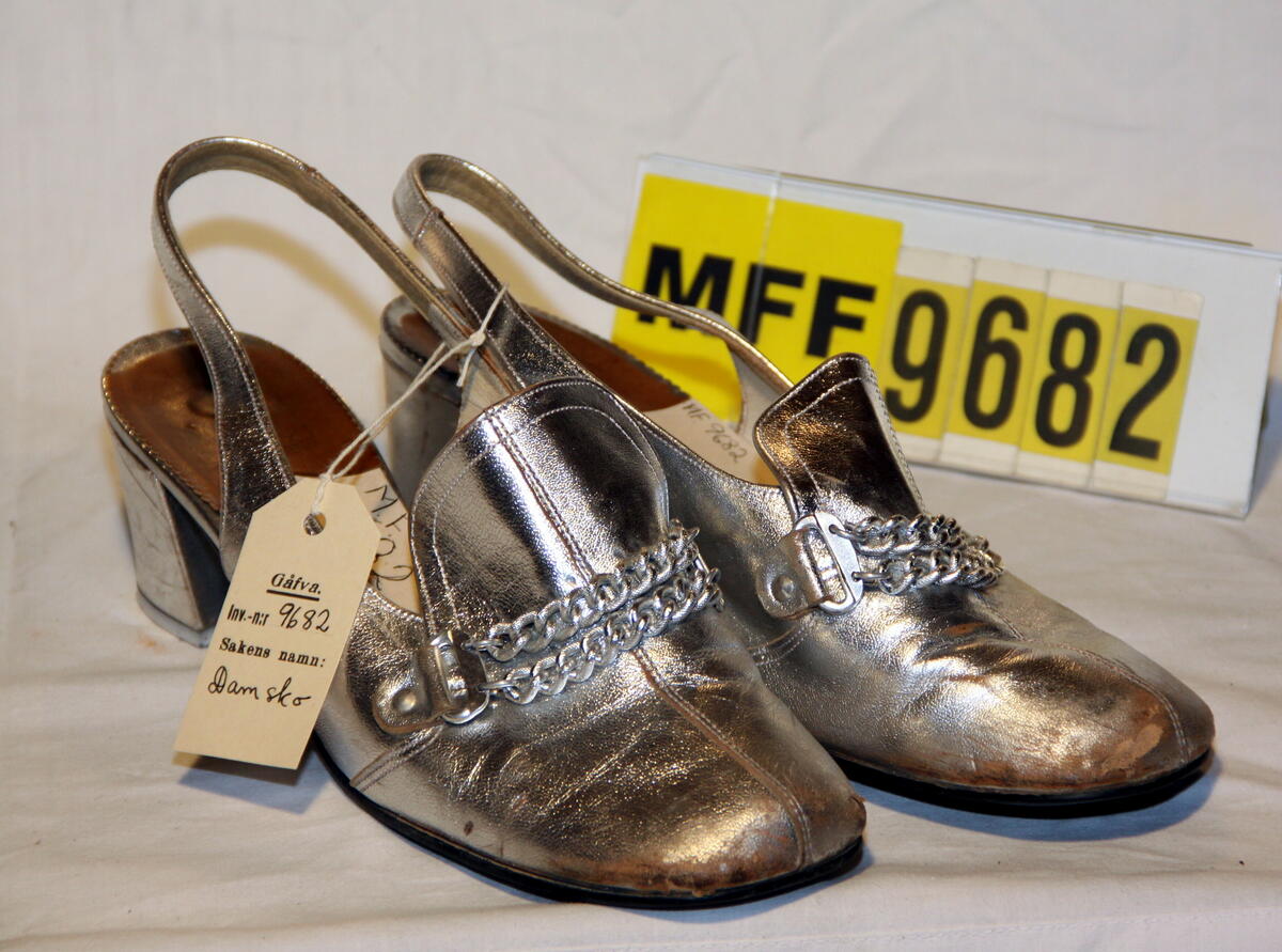 "Damskor." Gåva av: "Barbro Landell, Sundsvall." (liggaren)

"Damsko, par: Sandalett i silver, storl. 5." (inv.prot.)