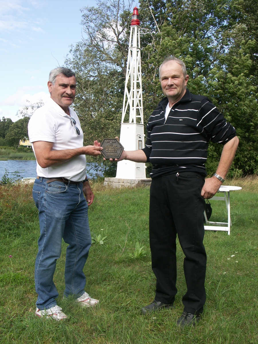 Göran Klinghag och Kenneth Lindberg, Uppsala kommun, håller i en plakett vid invigningen av byggnadsminnet Flottsunds fyr, Uppland, 27 augusti 2009