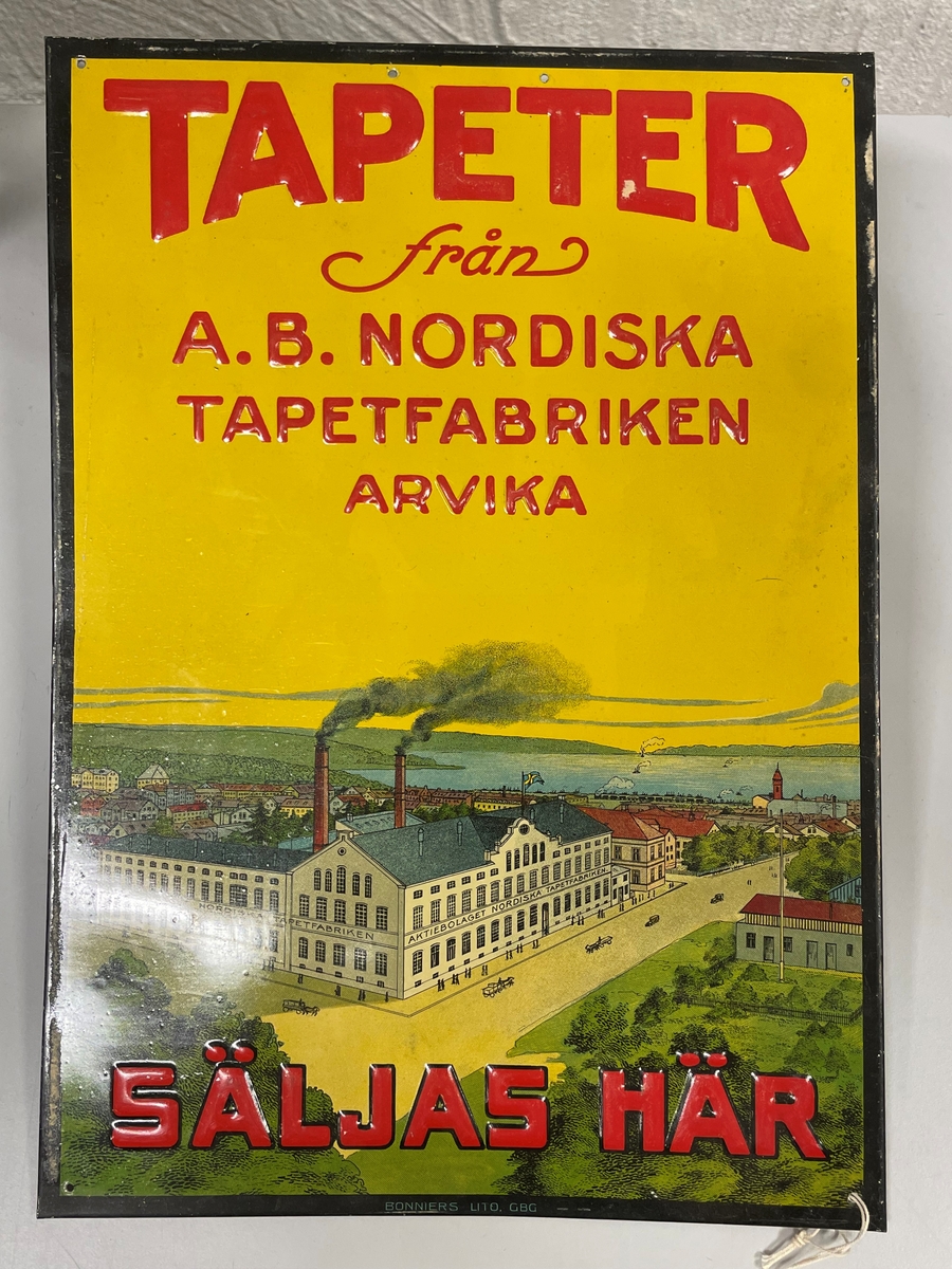 Skylten har en tryckt bild av tapetfabriken med Arvika bebyggelse och Glafsfjorden med omnejd i bakgrunden. Två tredjedelar av bilden upptas av gul himmel med präglad text. Bilden inramas av tryckt svart kant. I varje hörn ett hål samt i övre delens mitt 2 hål för upphängning.
   Ett lapp med texten som har samband med tapetfabriken i Arvika finns i Värmlands museets arkiv.