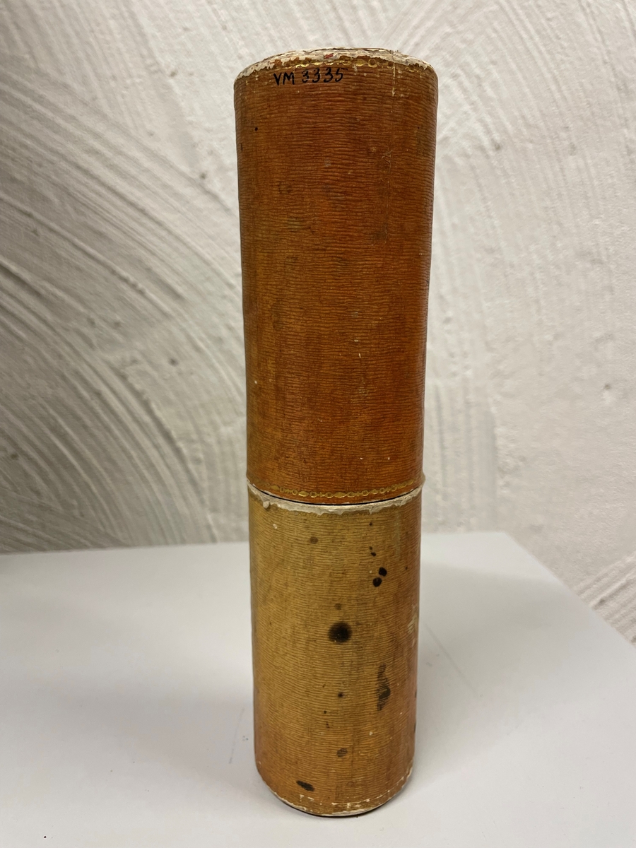 Cylinderformat fodral av papp, klädd med gulbrunt papper. Kanterna vid öppningen har förgyllda bårder. Ena kortänden har initialerna E. T. i förgyllning. Inuti ligger en kort fjäderpenna.