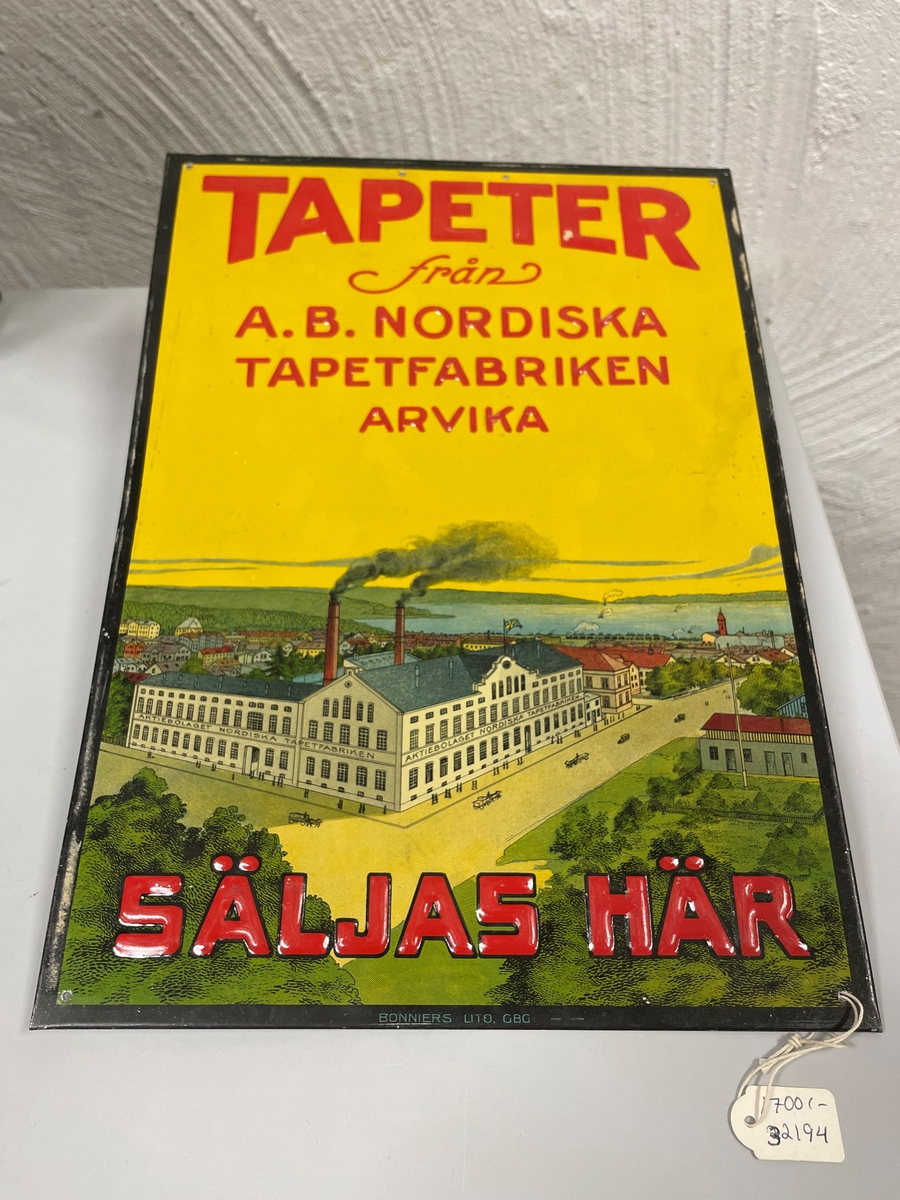 Skylten har en tryckt bild av tapetfabriken med Arvika bebyggelse och Glafsfjorden med omnejd i bakgrunden. Två tredjedelar av bilden upptas av gul himmel med präglad text. Bilden inramas av tryckt svart kant. I varje hörn ett hål samt i övre delens mitt 2 hål för upphängning.
   Ett lapp med texten som har samband med tapetfabriken i Arvika finns i Värmlands museets arkiv.