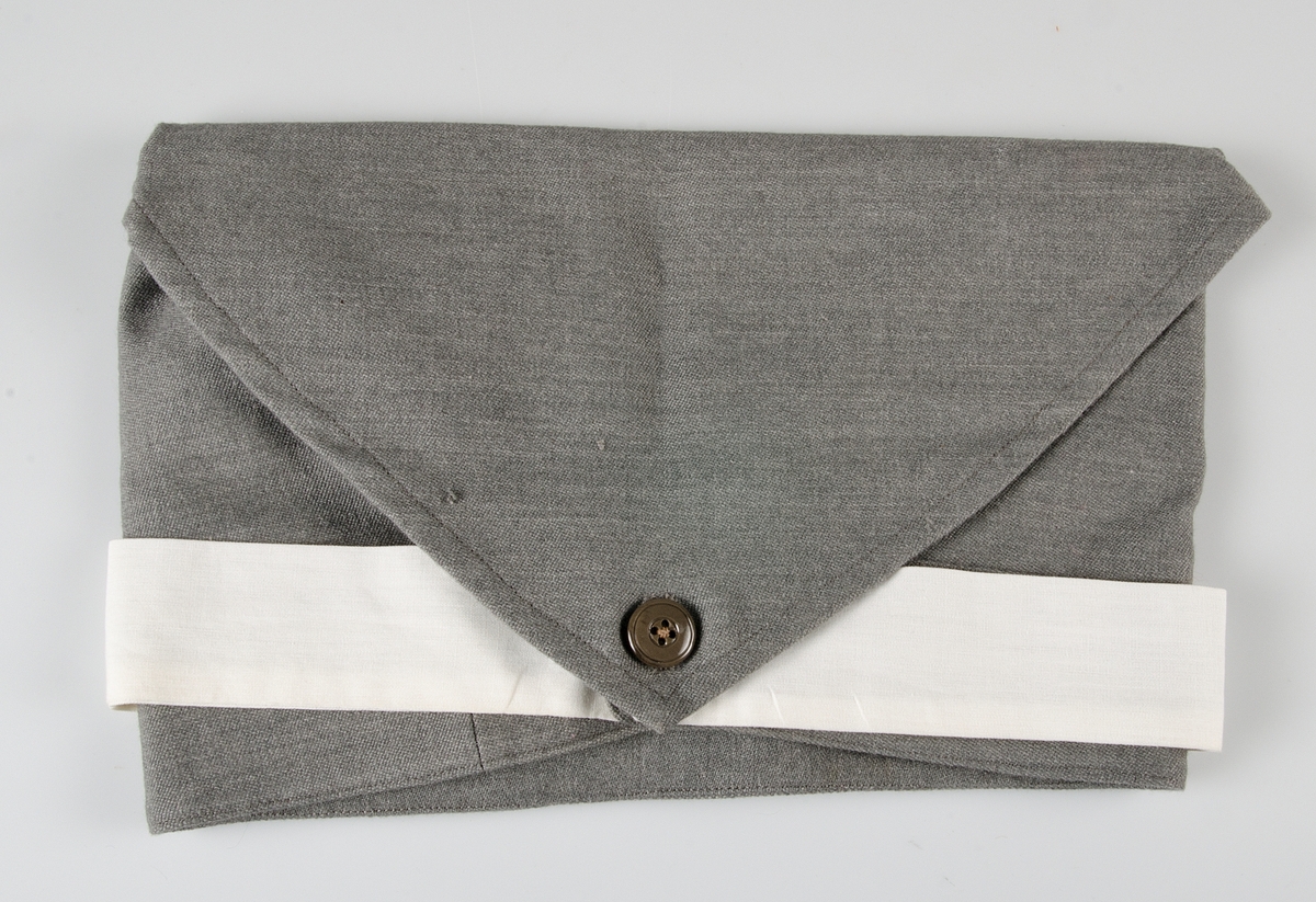 Klänning av grått ylletyg. Knälång klänning med isydd lång ärm. Kjolen har två nedsydda vecka fram och två fickor och ett veck bak. Knäppning från krage till midja med tio grå knappar.Knappar i handled.  Påsydda axelklaffar. Manchetter i vitt, löstagbara, påknäppt vit krage av konstsilke.Till klänningen hör skärp med knappar och knapphål och huvudbonad av samma tyg, snibb med knappar bak, påknäppt itt band fram med blått broderi: S.L.K (Sveriges lottakår). Mössan är märkt med samma UM nummer som klänningen.  Klänningen har löstagbara märken på axelklaffarna : 2. På bröstet  flera märken se UM 25.916. Ärmlängd 48 cm, axelbredd 48 cm, vidd 200 cm.