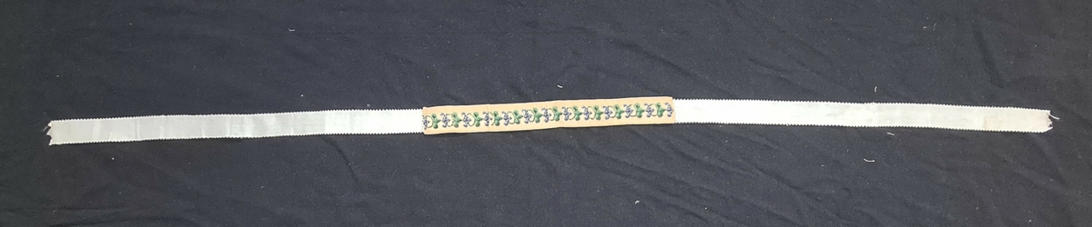 Tre olika strumpeband. Det breda bandet har målat motiv. Ett band är pärlbroderat. Ett band har broderat rosenmönster. 1=B. 6 cm L. 105 cm  2=3 cm L. 114 cm  3=B. 2,5 cm L. 131 cm. Givaren har ärvt föremålen av Anna Geijer, gift med prosten Oskar Geijer, Frändefors. Troligen kommer banden från prostens första hustru som var född 1841.