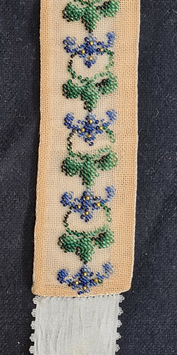 Tre olika strumpeband. Det breda bandet har målat motiv. Ett band är pärlbroderat. Ett band har broderat rosenmönster. 1=B. 6 cm L. 105 cm  2=3 cm L. 114 cm  3=B. 2,5 cm L. 131 cm. Givaren har ärvt föremålen av Anna Geijer, gift med prosten Oskar Geijer, Frändefors. Troligen kommer banden från prostens första hustru som var född 1841.