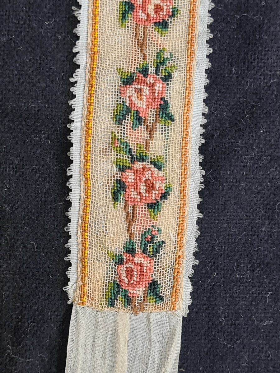 Tre olika strumpeband. Det breda bandet har målat motiv. Ett band är pärlbroderat. Ett band har broderat rosenmönster. 1=B. 6 cm L. 105 cm  2=3 cm L. 114 cm  3=B. 2,5 cm L. 131 cm. Givaren har ärvt föremålen av Anna Geijer, gift med prosten Oskar Geijer, Frändefors. Troligen kommer banden från prostens första hustru som var född 1841.