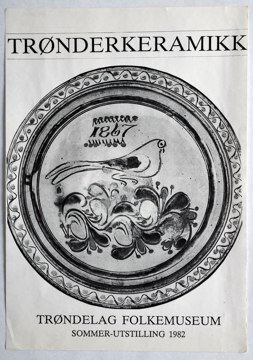 En plakat som ble produsert for/av Trøndelag Folkemuseum i forbindelse med utstillingen "Trønderkeramikk" som ble avholdt ved museet sommeren 1982. Motivet er et keramikkfat med fugledekor, rosemaling og border. Plakaten er i sort/hvitt.