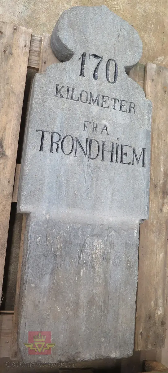 Rektangulær massiv stein, formet som en løk i toppen. Grå. Har teksten: 170 KILOMETER FRA TRONDHIEM. Teksten er preget inn i steinen og malt svart. Steinen ser ut til å være skjøtet sammen av to deler. Bærer preg av oppussing.