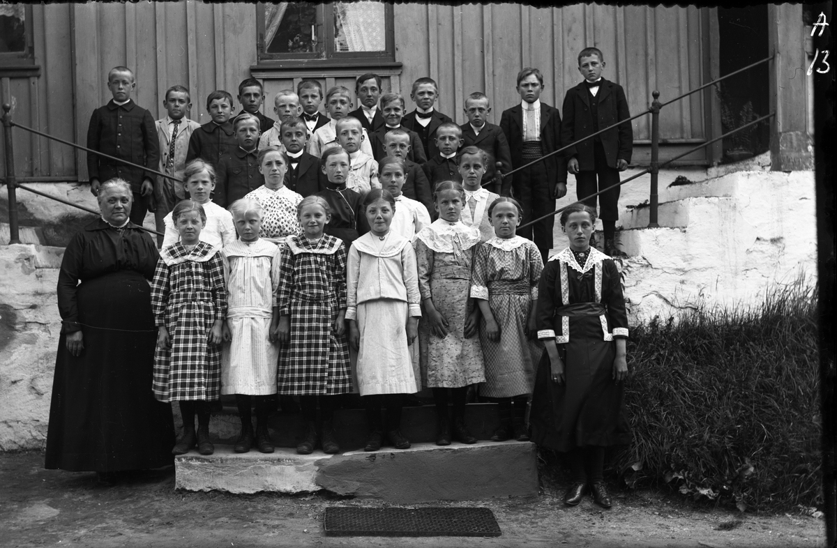 Folkskollärarinnan Constance Engström med elever på trapporna till Sällstorps första skolhus, som låg i Lugnet. Fotografiet lär vara taget omkring år 1914. Constance hade tjänsten vid folkskolan åren 1891-1921.

Se Bild 2 för numrering av barnen, överst fr v: nr 2 Ragnar Börjesson, Karlsberg; nr 5 Horse Herman (f. 1904); nr 6 Karl-Ander Edvardsson, Lellehansa (f. 1903); nr 8 Sväs Anders, Ulvatorp (f. 1902); nr 9 Torkels Gunnar (f 1903); nr 10 Kålhage Sven (f 1903); nr 11 Sväs Ragnar, Holmåkra (f 1903); nr 12 på trappan Kulla Nils (f 1902). Framför dem: nr 15 Sväs Gunnar, Ulvatorp (f. 1904); nr 16 Ivar M, Hästhagen (f. 1905); nr 17 troligen Sväs Härder, Holmåkra (f. 1905); nr 18 troligen Annersa Ivar (f. 1905). Flickorna rad 2 fr v: nr 19 Hilma J, Hansa; nr 23 Gerda J, Hansa. Främsta raden: nr 30 Vävars Ester (f. 1905); nr 31 Gunnars Selma (f. 1903).