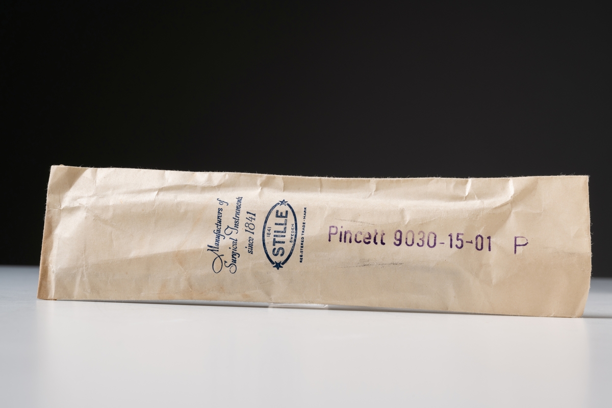 Pincett i originalförpackning, utrustning inom civilförsvar. Av rostfritt stål, märkt: " * STILLE SWEDEN * ". Oanvänd. 

Originalförpackning, vit, rektangulär påse, öppen i ena änden. På påsen tryckta texter: "Manufacturers of Surgical Instruments since 1841" och "1841 STILLE SWEDEN" samt  "REG.STERED TRADE - MARK". Stämplad: "Pincett 9030-15-01 P".

Se Historik.