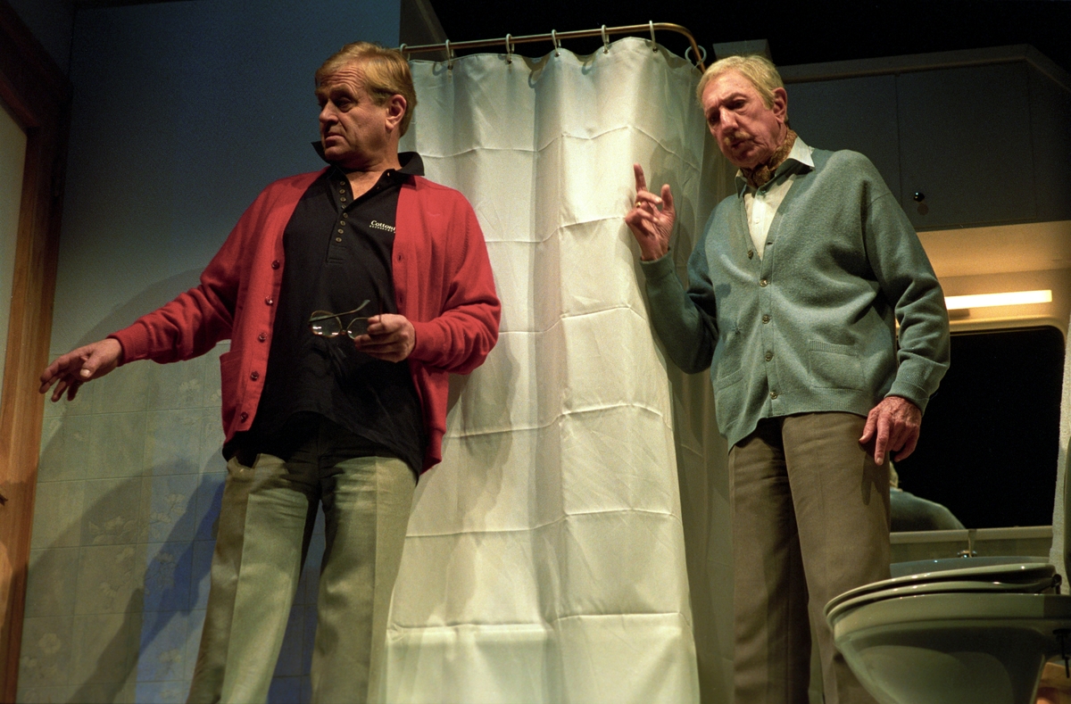 Scene fra Nationaltheaterets oppsetning av Alan Ayckbourns "Monki Bisniss". Jack og Ken Ayres står i et baderom foran et dusjforheng. Forestillingen hadde premiere 8. september 1989. Toralv Maurstad hadde regi og medvirkende var blant annet Tor Stokke som Jack, Kari Simonsen som Poppy og Leif Juster som Ken Ayres.