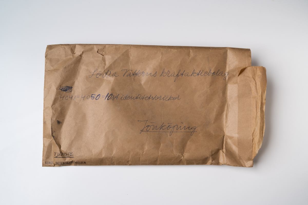 Id-brickor, 10 st, i originalförpackning, utrustning inom civilförsvar. Runda brickor av metall präglade: E K 4041; E K 4042; E K 4043; E K 4044; E K 4045; E K 4046; E K 4047; E K 4048; E K 4049; respektive E K 4050. Brickorna är försedda med metallkedja. Varje bricka förvaras i en liten papperspåse försluten med mässingsklämma. Påsarna är stämplade med respektive nummer:  4041,  4042,  4043,  4044,  4045,  4046,  4047,  4048,  4049 och  4050. Oanvända. JM.568115:9:1-10.

Vid förvärvstillfället var påsarna inlindade i tidningspapper ur Göteborgs Handels- och Sjöfarts-tidning, daterad 1 mars 1957. Paketet var placerat i ett brunt kuvert, stämplat: "TJÄNSTE. KUNGL VATTENFALLSSTYERELSEN". På kuvertet finns handsrkriven text: "Södra Vätterns Kraftaktiebolag 4041-4050 = 10 st identitetsbrickor Jönköping".

Oanvända.

Se Historik.