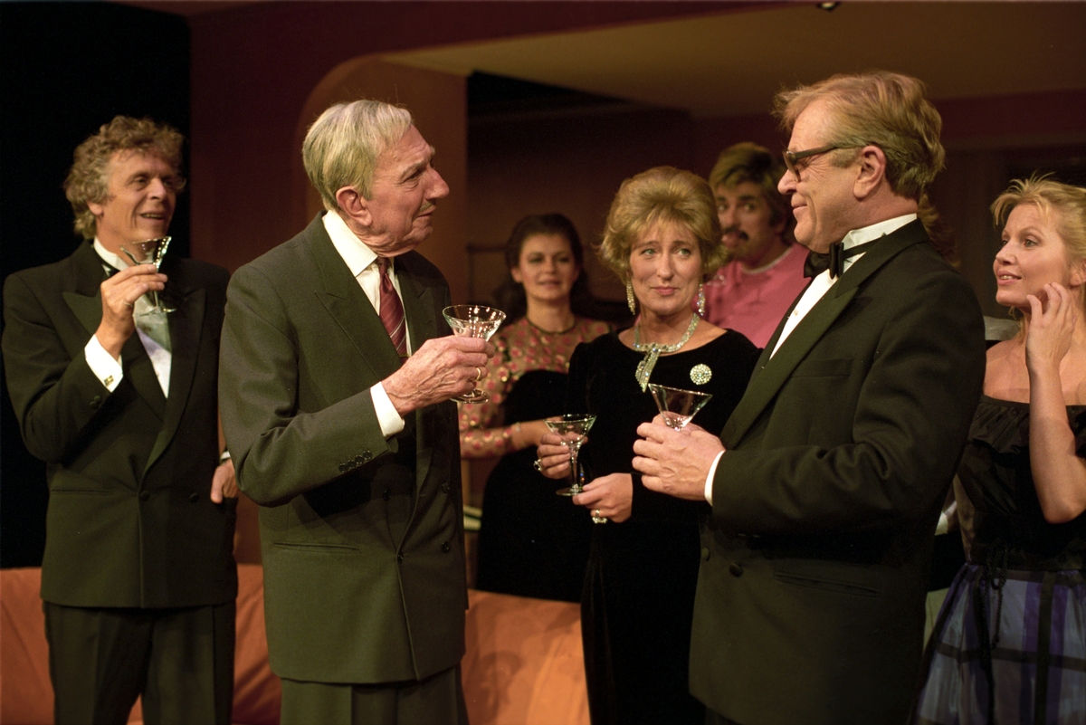 Scene fra Nationaltheaterets oppsetning av Alan Ayckbourns "Monki Bisniss". Desmond, Ken Ayres, Yvonne, Jack og Tina snakker sammen med cocktailglass i hendene. Forestillingen hadde premiere 8. september 1989. Toralv Maurstad hadde regi og medvirkende var blant annet Tor Stokke som Jack, Kari Simonsen som Poppy og Leif Juster som Ken Ayres. 