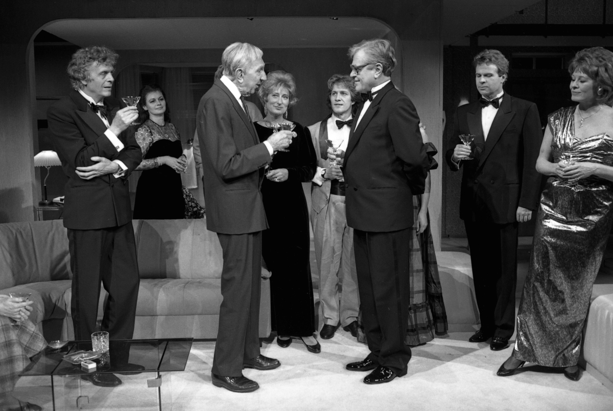 Scene fra Nationaltheaterets oppsetning av Alan Ayckbourns "Monki Bisniss". Ni kvinner og menn kledd for fest står i en gruppe, der de prater og drikker. Forestillingen hadde premiere 8. september 1989. Toralv Maurstad hadde regi og medvirkende var blant annet Tor Stokke som Jack, Kari Simonsen som Poppy og Leif Juster som Ken Ayres. 