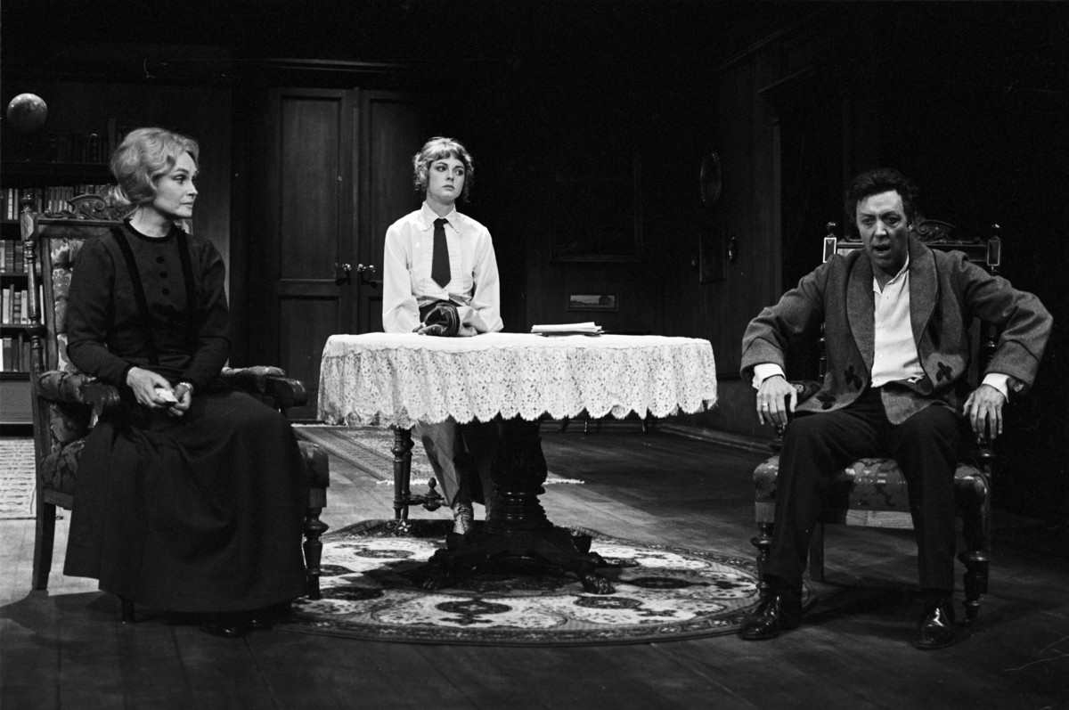 Scene fra Nationaltheaterets oppsetning av Henrik Ibsens "En folkefiende". Forestillingen hadde premiere 27. september 1979. Charles Marowitz hadde regi, og medvirkende var blant annet Per Theodor Haugen som Dr. Thomas Stockmann, Ingerid Vardund som Fru Stockmann og Tor Stokke som Peter Stockmann. 