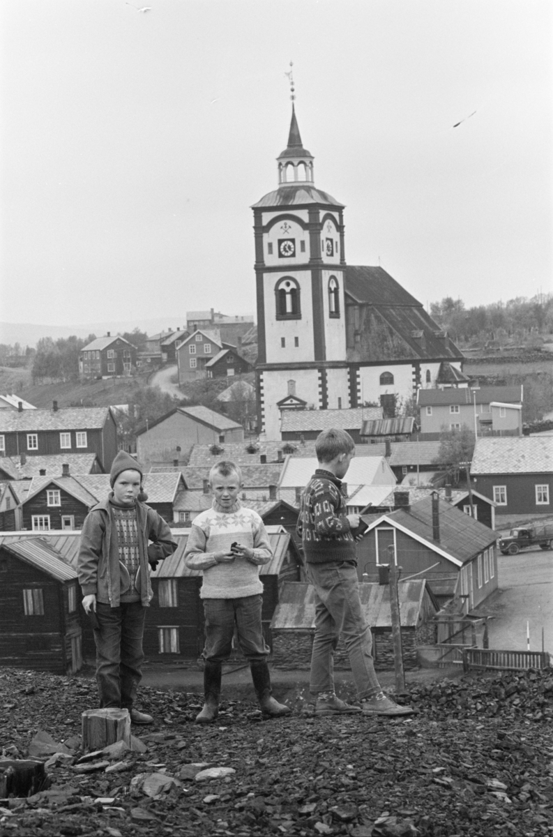 Barn leker i slagghaugene ved Røros. Kirken sees i bakgrunnen.