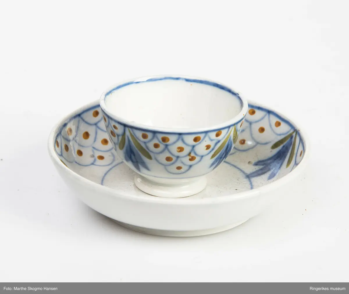 Dokkeserviset består av to skåler (G&H), to boller eller kopper (uten hank) (E&F), en fløtemugge (C), en sukkerkopp (D), en tekanne (B) og en kaffekanne (A). Kannene har tut og hanker, og lokk. Tuten på kaffekanna har vært brukket, og er limt på igjen. Sukkerkoppen har også lokk. Lokkene har små knopper som håndtak, disse er blå på toppen. Sukkerkoppen har ikke håndtak, men har lokk. Serviset er dekorert med blått, oransje, og grønt. Noen av dekorasjonene er blomsteraktige, mens andre er buer med prikker inni.
