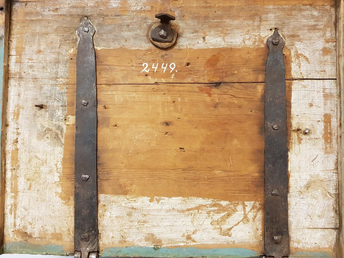 Skrinet har raka former och ett platt lock på ett par gångjärn. Två långa järnband utgår från gångjärnen och är fastspikade i skrinets baksida och lockets insida. Skrinets hörn är sinkade och varje sida dekorativt snidad med sexbladig blomma inom en cirkel i mitten och en stjärnformig dekor på sidorna. Skrinet är blåmålat. Det finns en låsanordning framtill. Skrin, av barrträ. Målat i ljust grönt. Rikt ornerat i karvsnitt, kilsnitt m.m. Lockets mitt med cirkelstjärna omgiven av korsställda, hjärtformiga ornament. Sidorna likaledes med cirkelstjärnor och hjärtformiga ornament. Lås. 