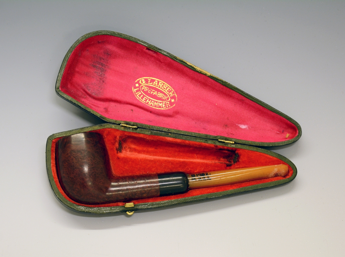 Pipe i etui. Brunt hode, gult munnstykke. Stemplet "Lillehammer G.L.". Etuiet stemplet "G. Larsen. Pipefabrik Lillehammer."