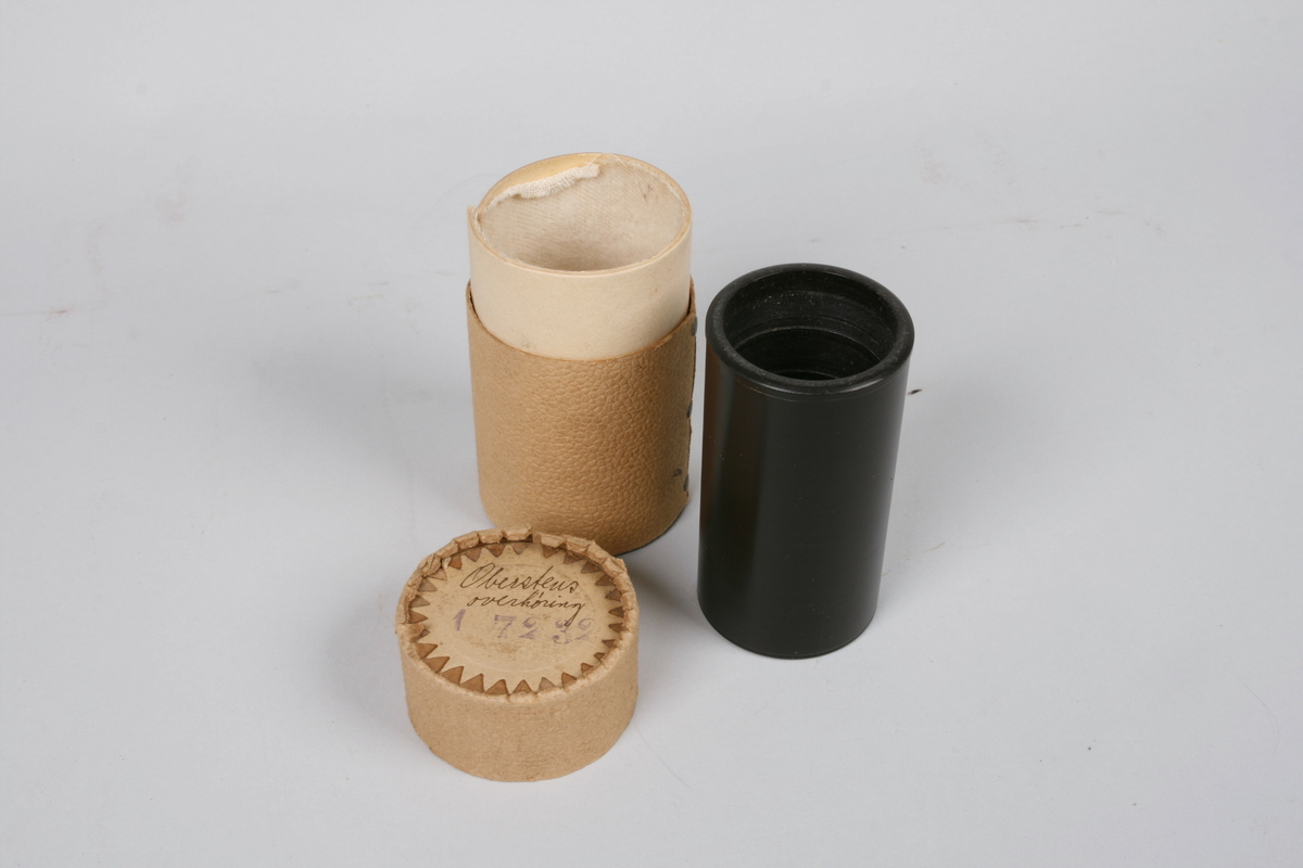 Fonografrull i svart materiale. Eske i papp med avtagbart lokk. Tekst om innholdet på lokket.