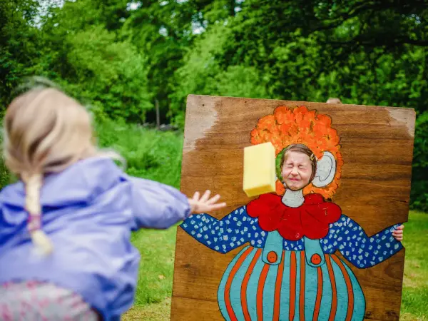 Barn kaster våt svamp på barn som står i sirkusramme.