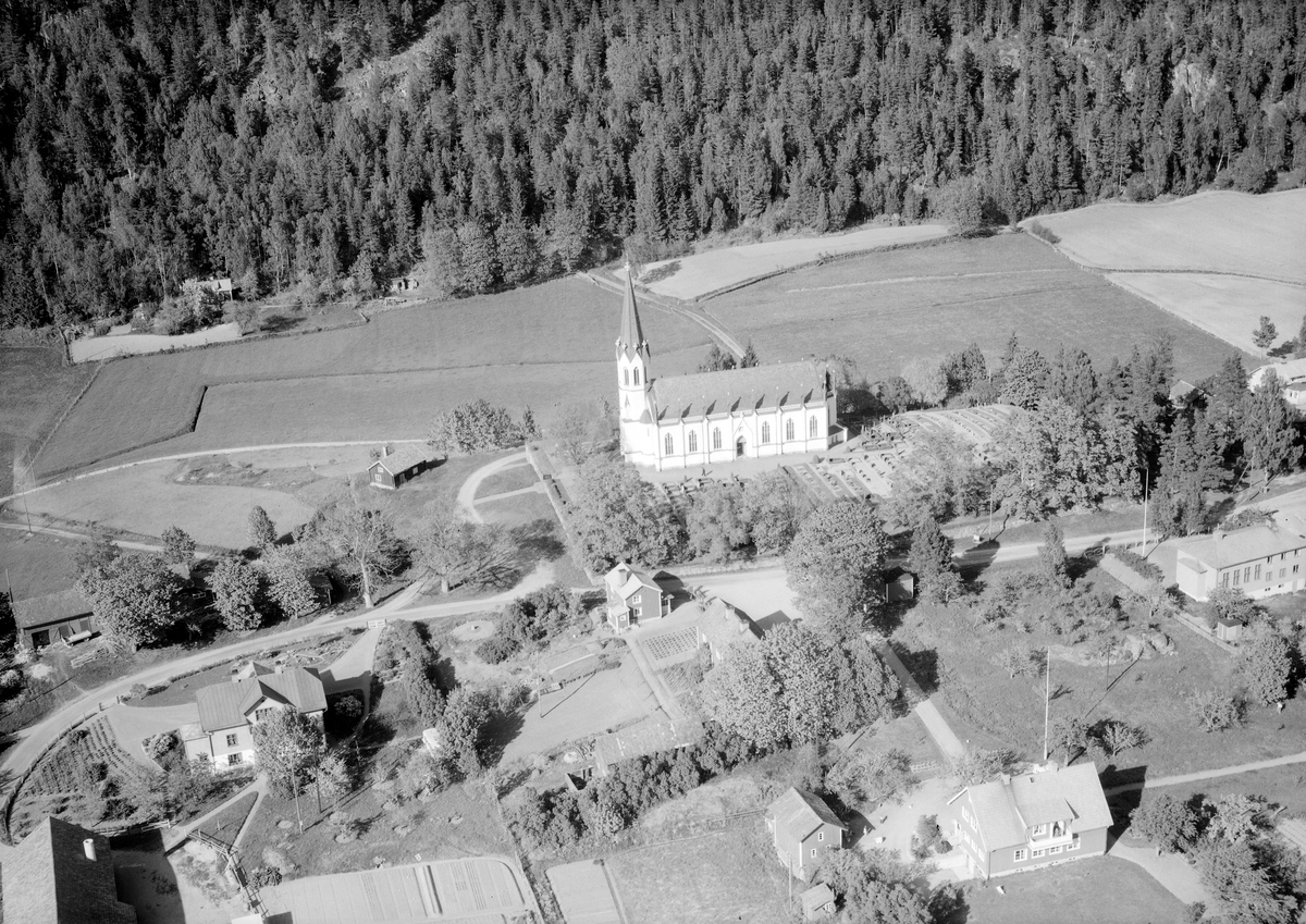 Del av Gärdserums kyrkby med ortens världsliga bebyggelse hitom landsvägen och dess smäckra kyrka därom. Den lilla byggnaden invid kyrkan tjänade upplysningsvis tidigare som socknens fattighus.