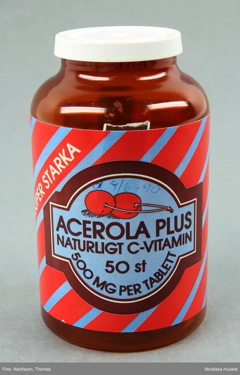 Huvudliggaren:
"Vitaminpillerburk, plast, gjuten. Brun klar cylindrisk, skuldra, kort hals, vitt snäpplock. Blå/röd etikett: Acerola c-vitamin. Tillv Naturprodukter Örebro. Anv Astrid Broman 1990, Ulrikag, Sthlm. H 10,5 Diam 6,5 cm. Gåva 30/10 1991 av Fröken Astrid Broman Ulrikagatan 2, Stockholm."