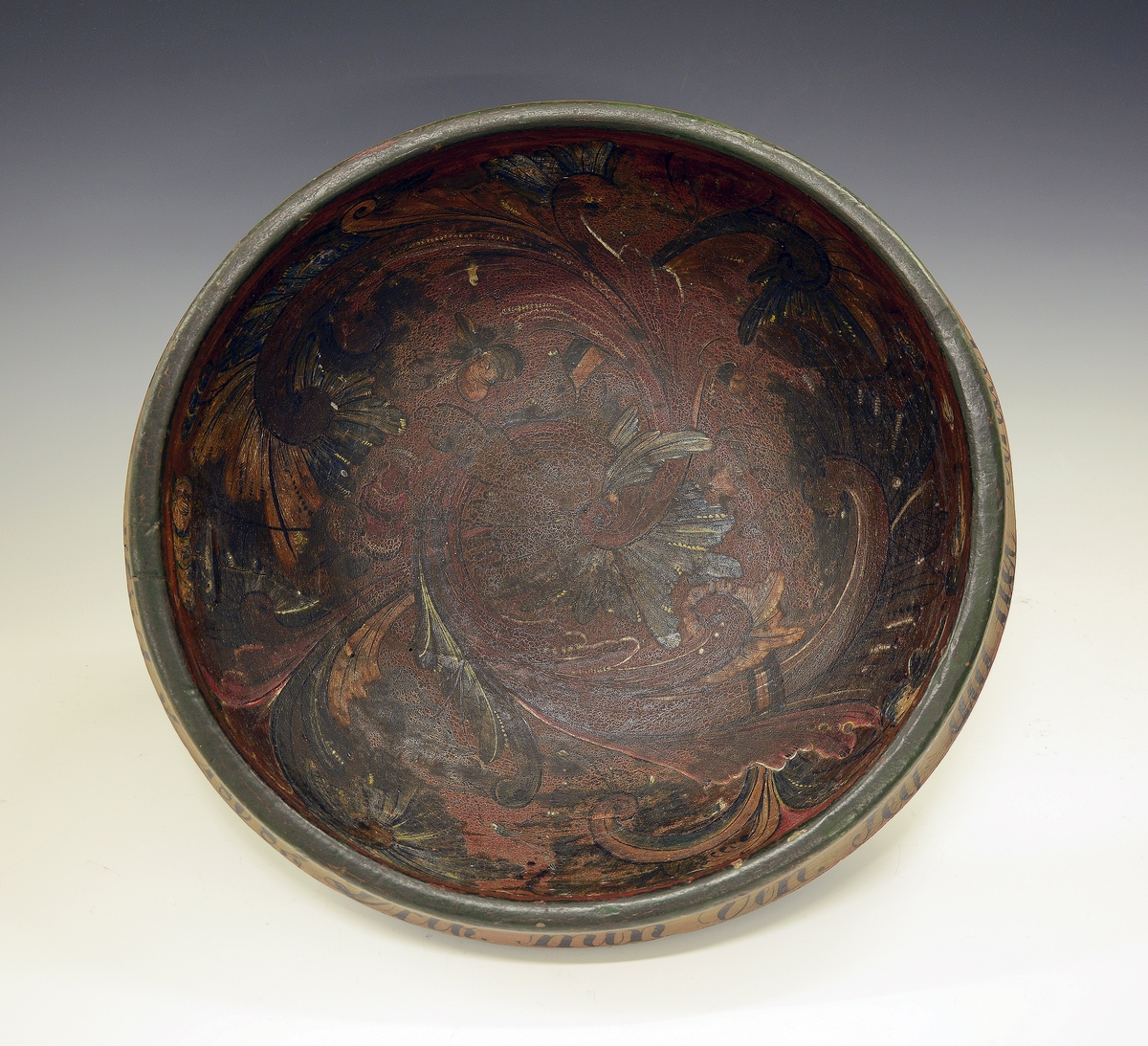 Rosemalt ølbolle. Fra protokollen: Ølbolle, svarvet med sterkt utstaaende ribbe, hvorfra en kant böier ind. Nyere overmaling, utenpaa malt lyseblaa med minjerød kant, hvorpaa indskriften: "Drik min Ven. Jeg dig det Under. Pust imelem og Giv dig stunder. G.G.S. 1868". Indeni er paa gulbrun bund  malt svære roser i c-oplæg og nærmest i Luraasstil; farver: rødbrunt, grønt, blaat, hvitt, gult; sort skrafering. Bollen er kinget.