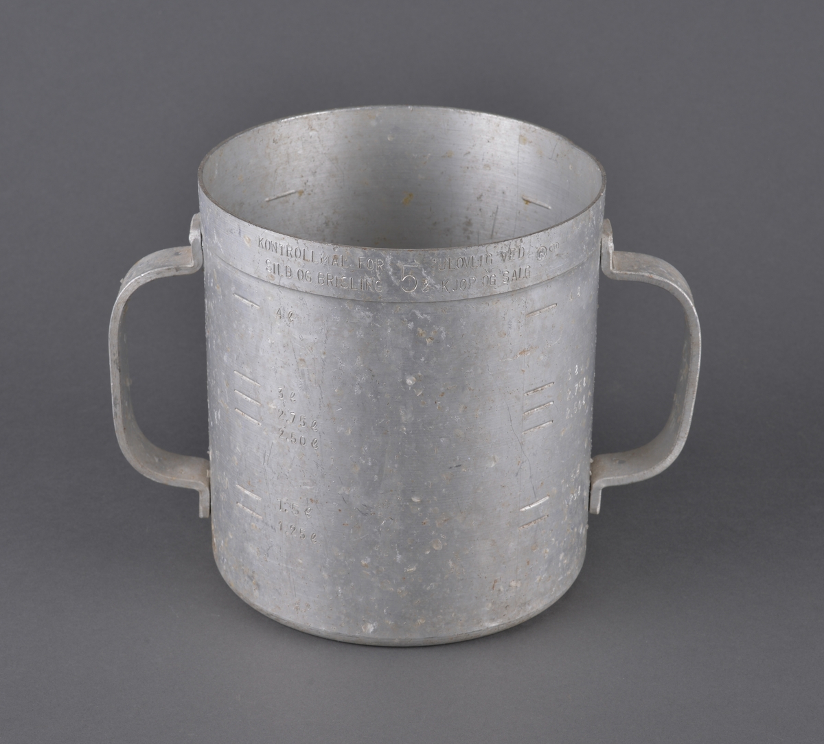 Målebeger for sild og brisling. Laget i aluminium (antatt) med måleskala på innside og utside. Tra totalt 5 liter. Handtak i sidene.

Spor av rist fra sild og brisling igjen på måleenhetens utside

Brukt av Fiskerisjefen i Sør-Trøndelag