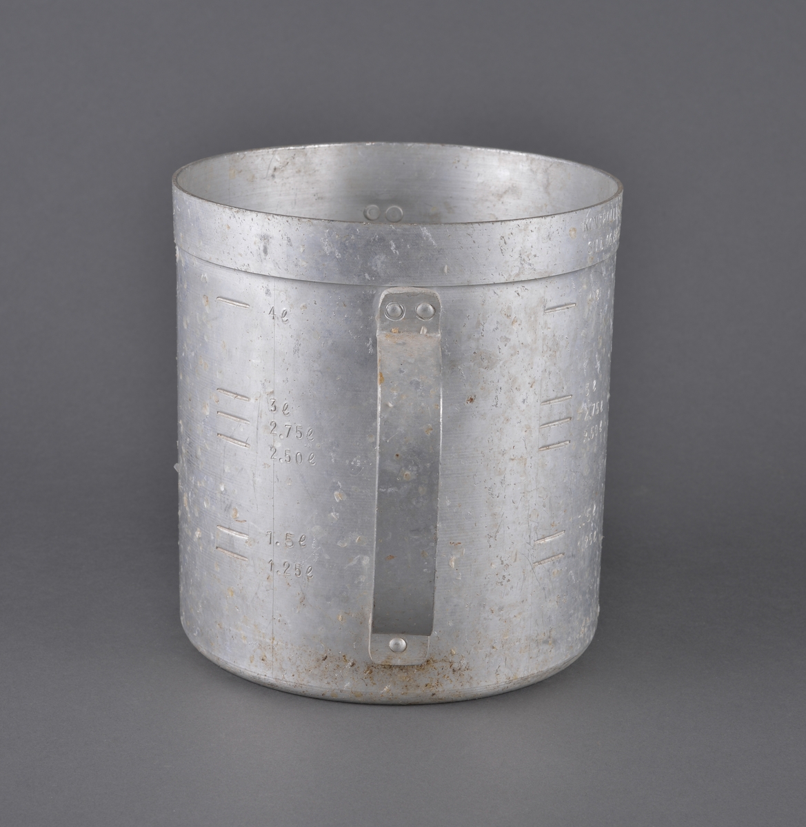 Målebeger for sild og brisling. Laget i aluminium (antatt) med måleskala på innside og utside. Tra totalt 5 liter. Handtak i sidene.

Spor av rist fra sild og brisling igjen på måleenhetens utside

Brukt av Fiskerisjefen i Sør-Trøndelag