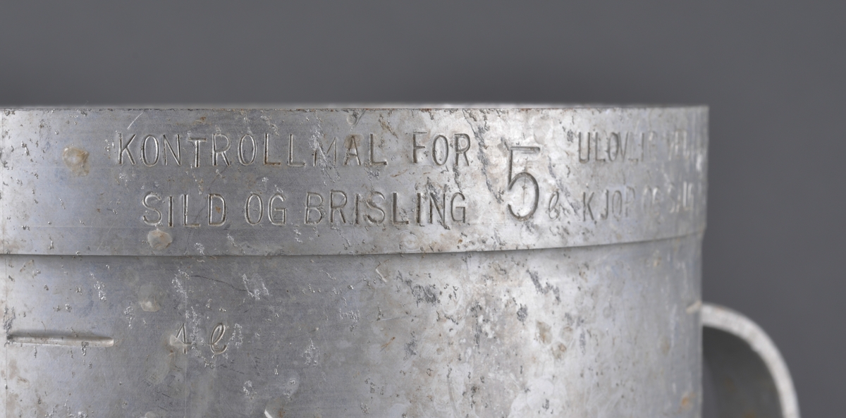 Målebeger for sild og brisling. Laget i aluminium (antatt) med måleskala på innside og utside. Tra totalt 5 liter. Handtak i sidene.

Spor av rist fra sild og brisling igjen på måleenhetens utside

Brukt av Fiskerisjefen i Sør-Trøndelag