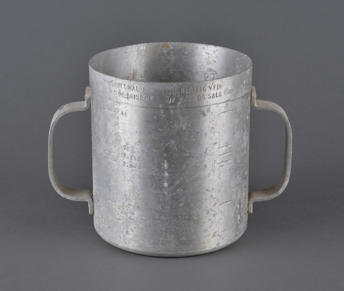 Målebeger for sild og brisling. Laget i aluminium (antatt) med måleskala på innside og utside. Tra totalt 5 liter. Handtak i sidene.

Spor av rist fra sild og brisling igjen på måleenhetens utside

Brukt av Fiskerisjefen i Sør-Trøndelag