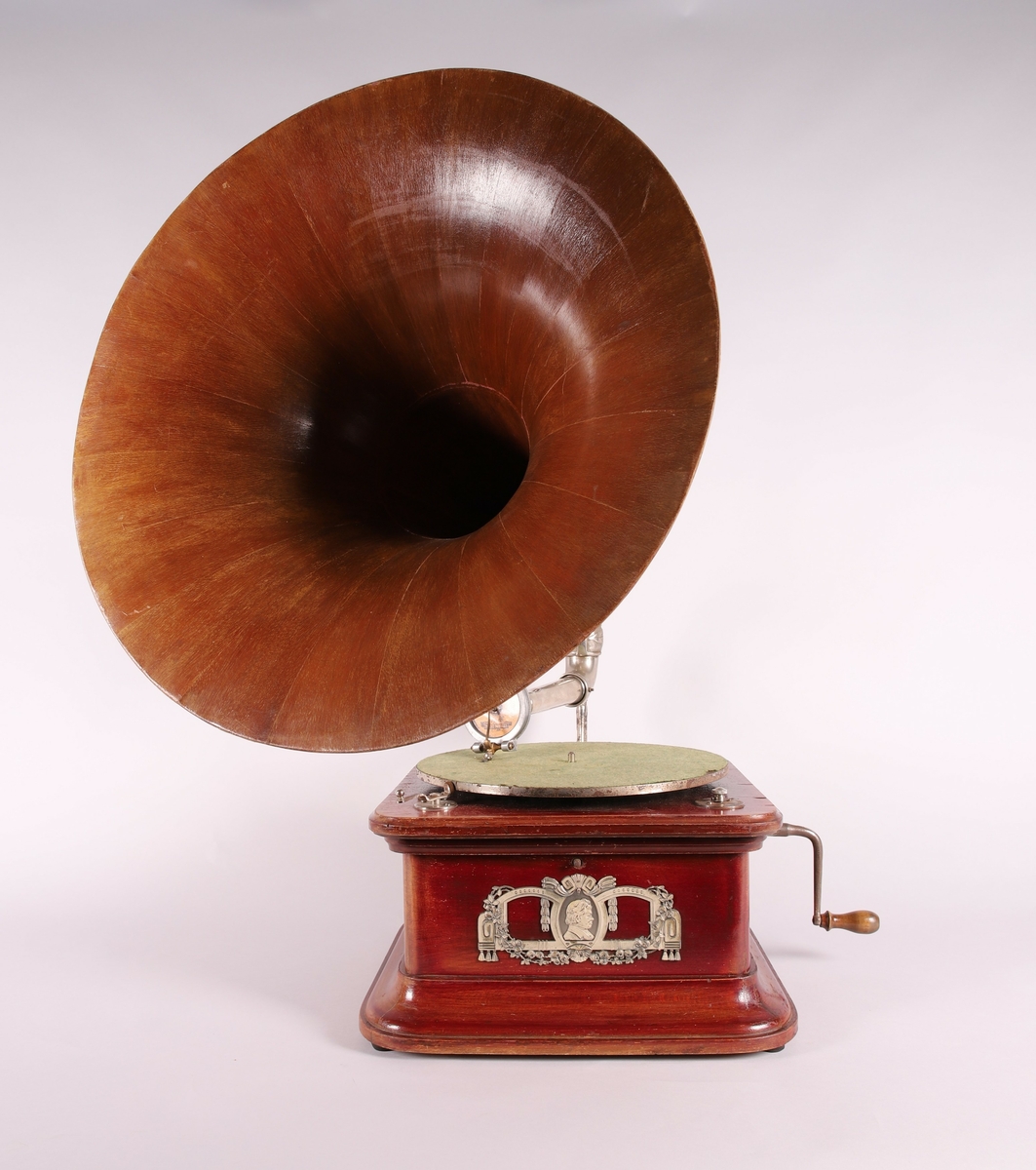 Pathéfon avspiller i treverk med finér. Sveiv på høyreside. Trakt i finér/treverk, med tynt lag av metall mellom lagene. Trakten kan løsnes fra instrumentet.