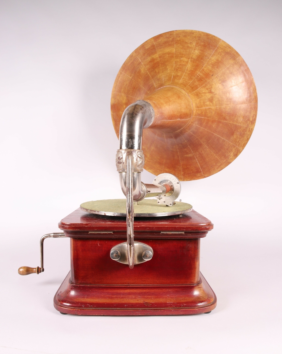 Pathéfon avspiller i treverk med finér. Sveiv på høyreside. Trakt i finér/treverk, med tynt lag av metall mellom lagene. Trakten kan løsnes fra instrumentet.