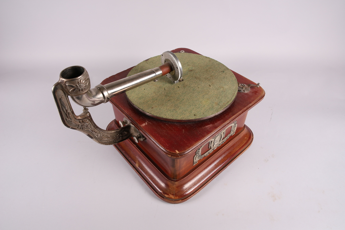 Pathéfon avspiller i treverk med finér. Sveiv på høyreside. Trakt i finér/treverk, med tynt lag av metall mellom lagene. Trakten kan løsnes fra instrumentet.