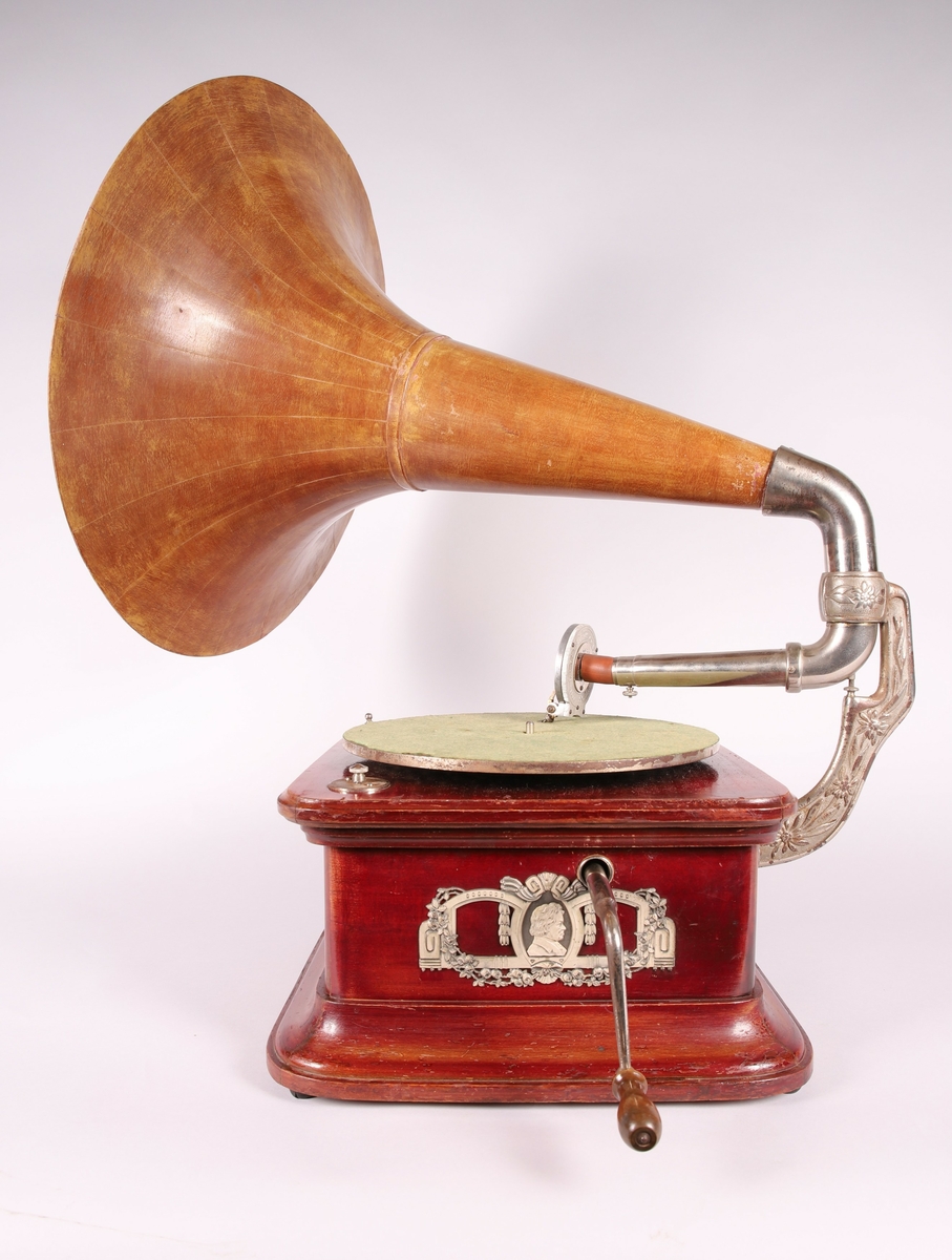 Pathéfon avspiller i treverk med finér. Sveiv på høyreside. Trakt i finér/treverk, med tynt lag av metall mellom lagene. Trakten kan løsnes fra instrumentet.