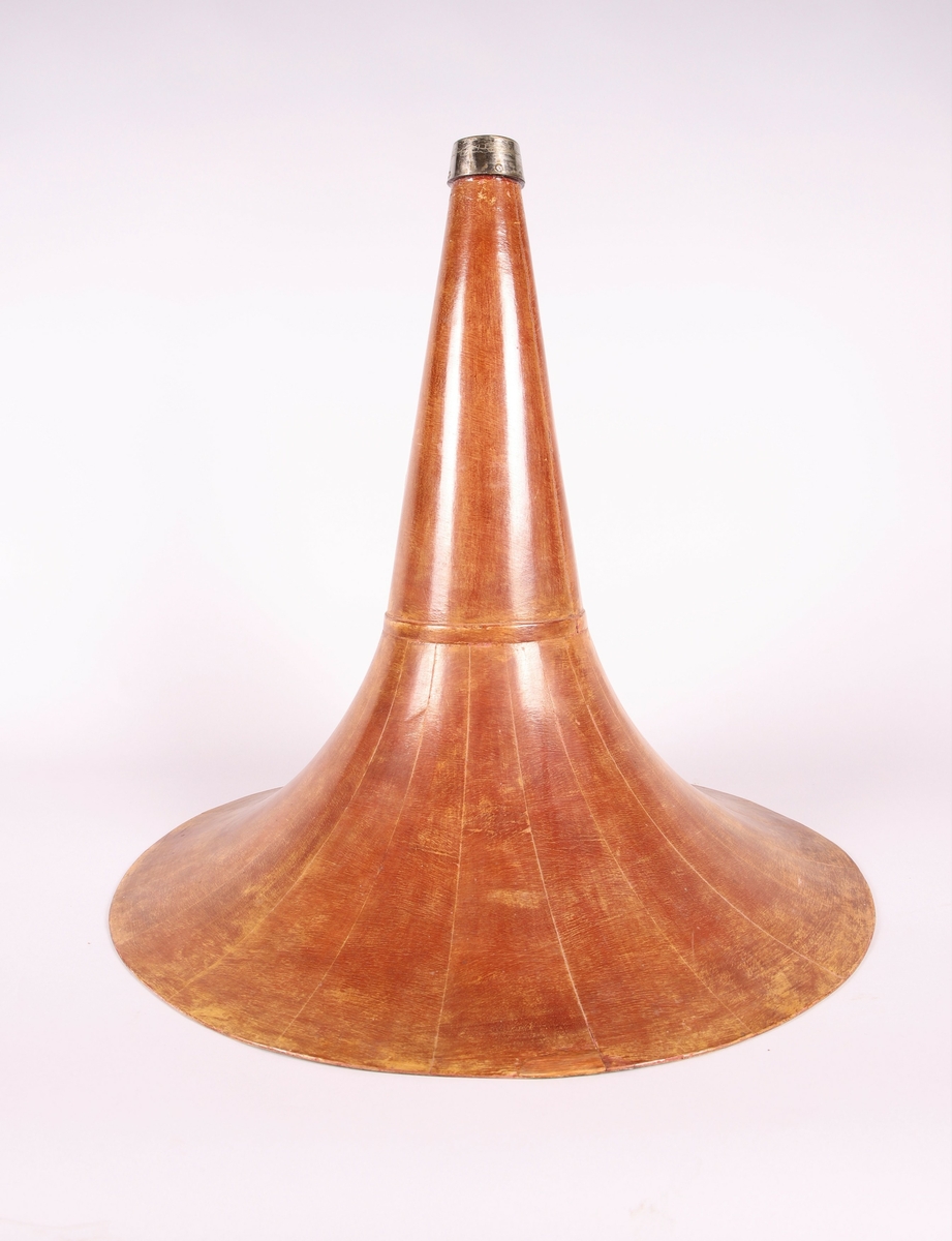 Pathéfon avspiller i treverk med finér. Sveiv på høyreside. Trakt i finér/treverk, med tynt lag av metall mellom lagene. Trakten kan løsnes fra instrumentet.