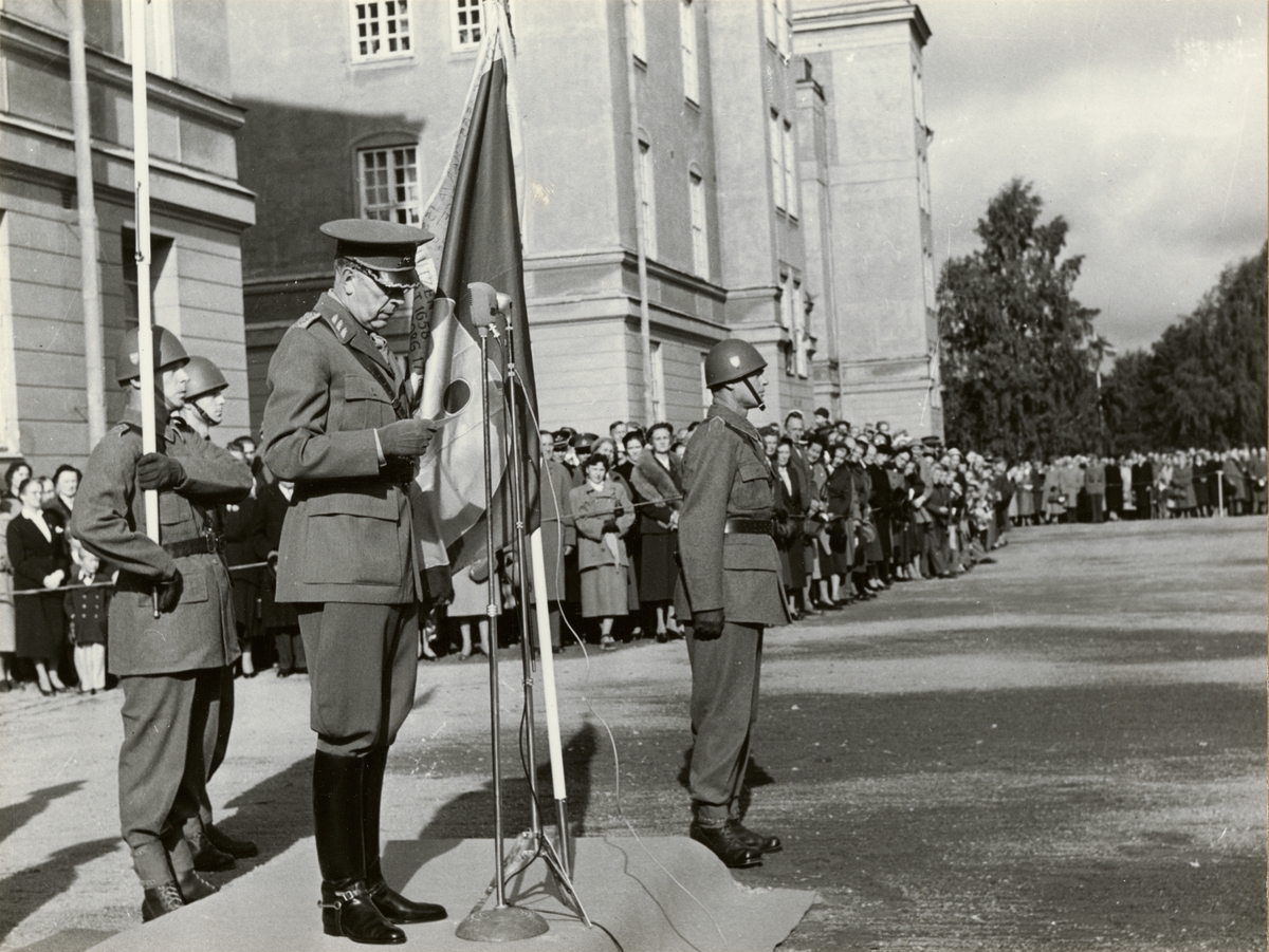 Text i fotoalbum: "Fanöverlämning 27 september 1955. Fr. v. kapten Kastenholm, fänrik Cronebäck, fanjunkare G.G. Andersson"