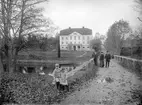 Vy mot Kvarns herrgård hösten 1906. Huvudbyggnaden återuppfördes efter en förödande eldsvåda i slutet av 1850-talet. För ritningarna stod den flitigt anlitade herrgårdsarkitekten August Nyström. Upplysningsvis hade den nedbrunna herrgården ritats av dennes far Abraham Nyström omkring år 1830. Personerna på bilden har inte identifierats men står sannolikt att finna hos godsets ägare, Pehr Orre, eller dess arrendator, Gustaf Melker Jacobsson.