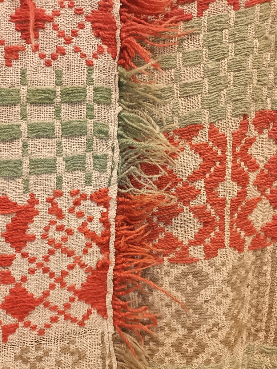 Sauma teppe i ullgarn. Bordar med firkantformer, kryss, åttebladsroser m.m. Teppet er handsauma,brodera med vevsaum på toskaftsbotn i lin. Botn er sauma saman på midten. Teppet har tre små lykker i den eine kortenden. Teppet er noko falma på rettsida, og er noko slite.