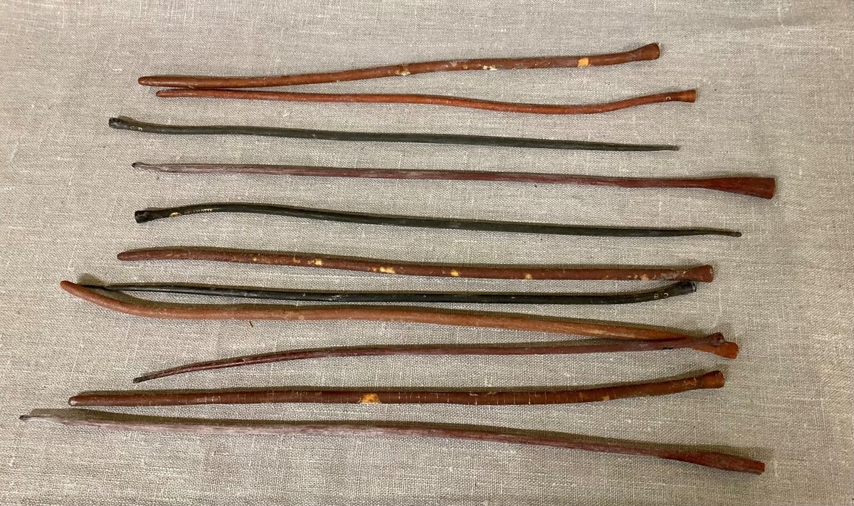 11 avlange pinneformede instrumenter i et gummilignende materiale. Bredere i den ene enden. Oppbevart i et glassrør.