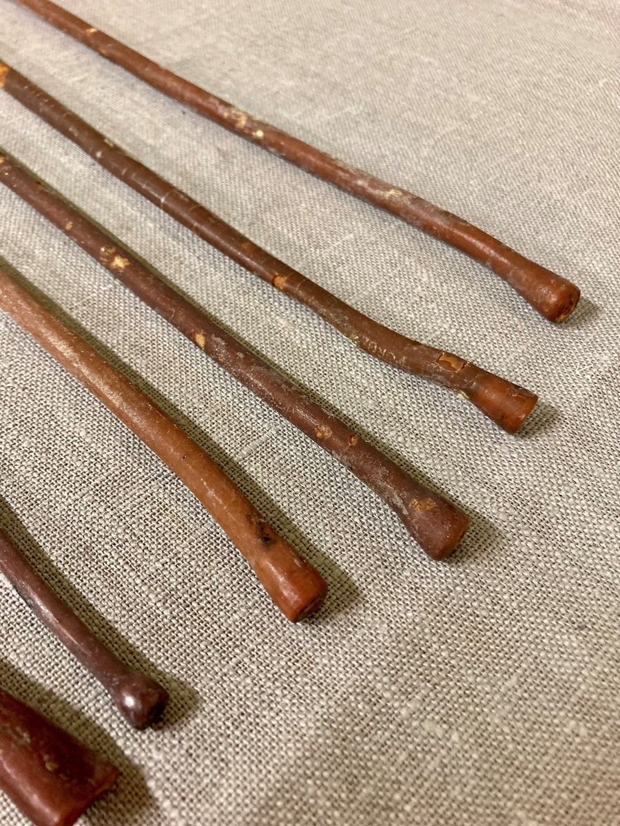11 avlange pinneformede instrumenter i et gummilignende materiale. Bredere i den ene enden. Oppbevart i et glassrør.